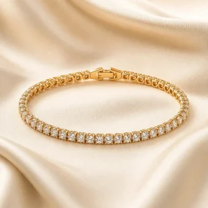 Gold-tone tennis bracelet with clear gemstone-style stones on ivory satin