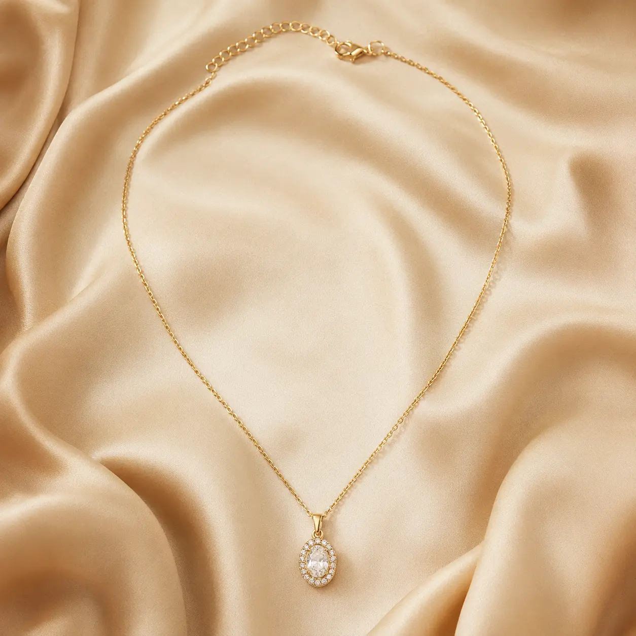 Gold-tone oval halo pendant necklace on champagne silk