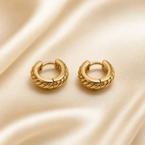Small rope-textured gold-tone huggie earrings on ivory satin