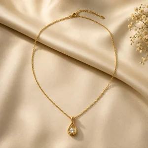 Gold-tone teardrop pendant necklace on ivory satin